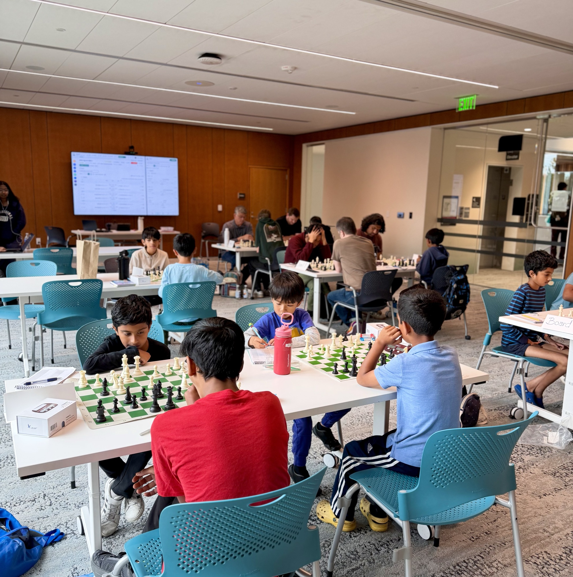 The Swiss section in play, with a young player in a red shirt at the front of the room.